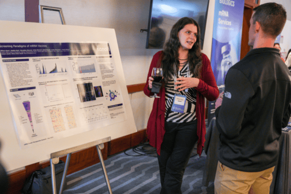 Conference attendees reviewing scientific posters and discussing research innovations.