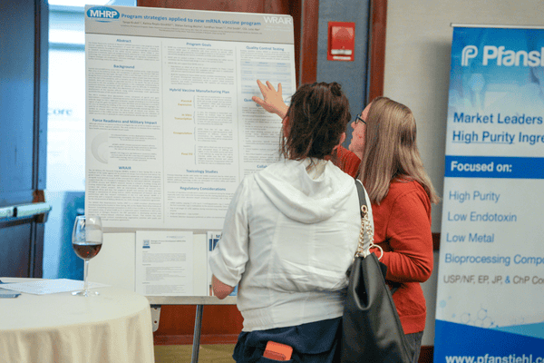 Research professional explaining a scientific poster to conference participants.