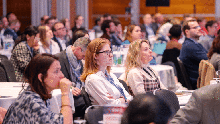 Conference delegates networking and attending presentations at a scientific industry summit.